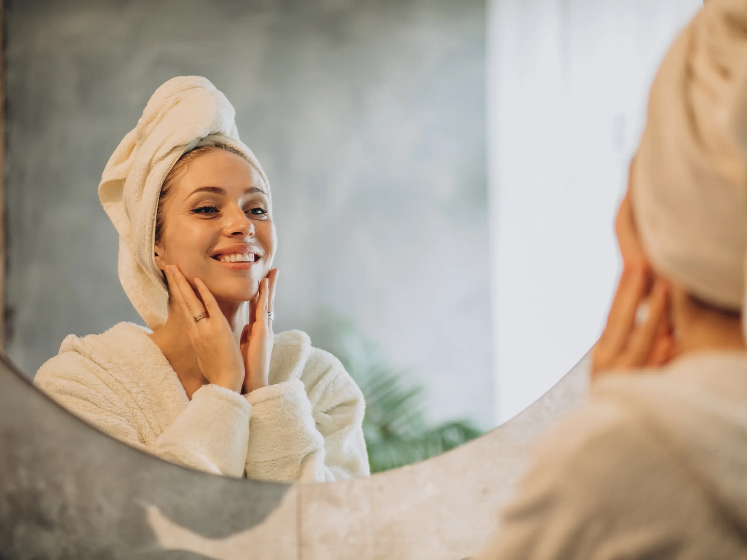 Woman in a bathrobe checking her skin in a mirror