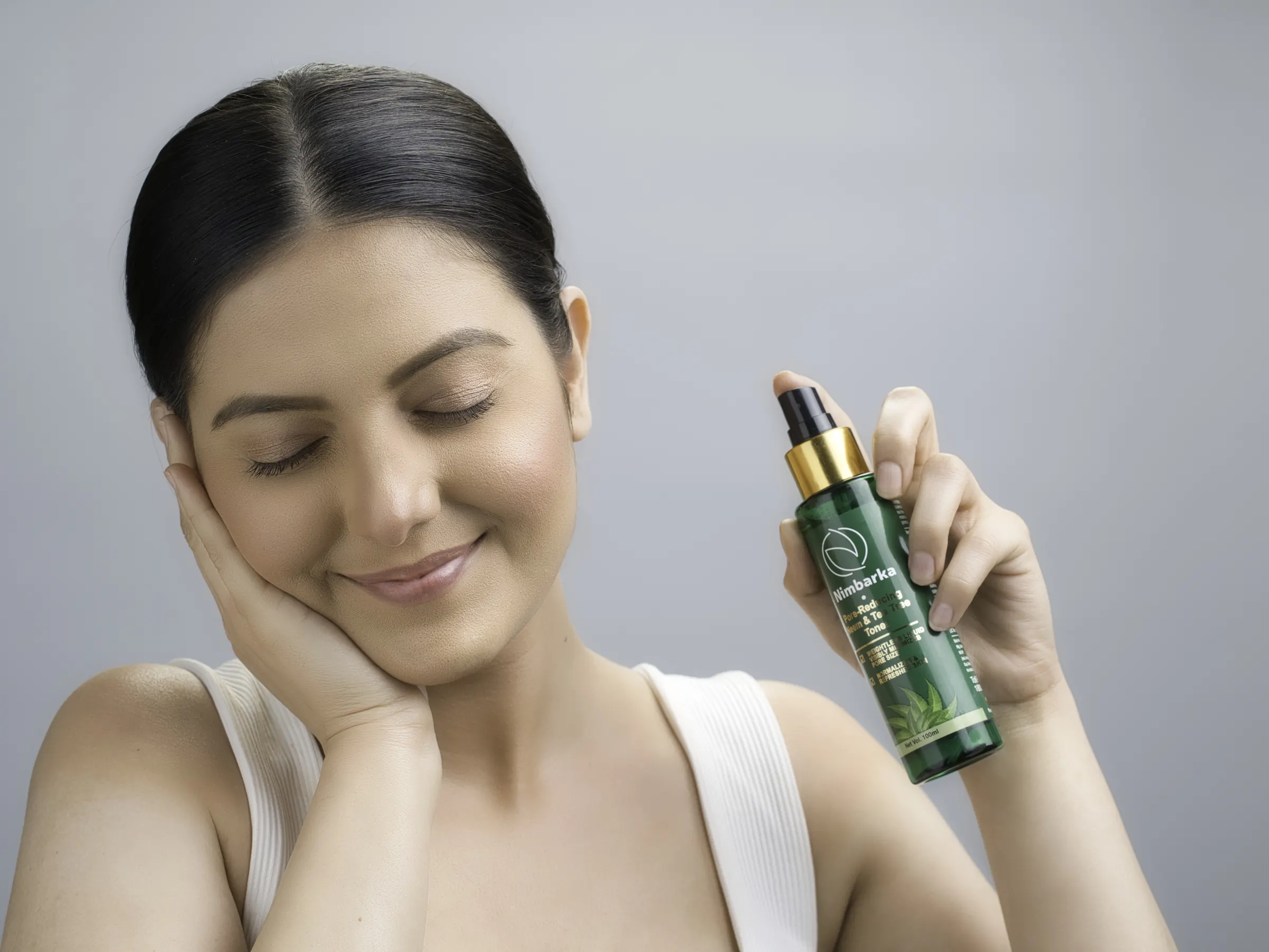 Nimbarka hair and skin tonic held up in a studio portrait